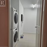 Washroom featuring light tile patterned floors and stacked washer / dryer - 