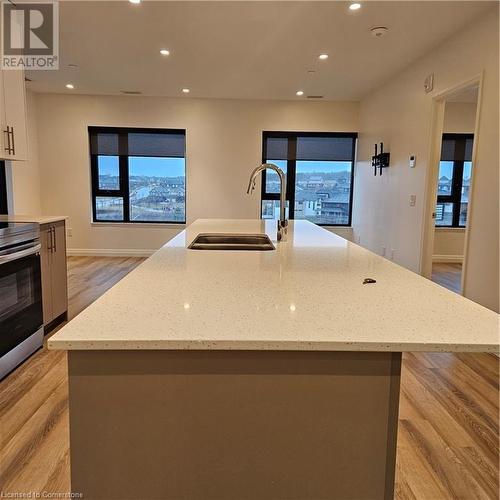 Kitchen with light stone countertops, white cabinetry, and an island with sink - 525 New Dundee Road Unit# 602, Kitchener, ON - Indoor Photo Showing Kitchen With Double Sink