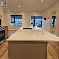 Kitchen with light stone countertops, white cabinetry, and an island with sink - 