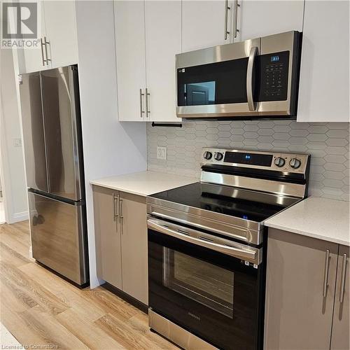 Kitchen featuring decorative backsplash, electric range, light hardwood / wood-style flooring, white cabinets, and fridge - 525 New Dundee Road Unit# 602, Kitchener, ON - Indoor Photo Showing Kitchen