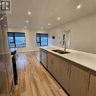 Kitchen with gray cabinets, dishwashing machine, sink, and light wood-type flooring - 