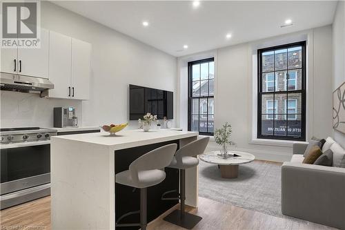 Kitchen with light hardwood / wood-style flooring, a center island, stainless steel stove, white cabinetry, and a breakfast bar area - 29 Main Street Unit# 201, Cambridge, ON - Indoor