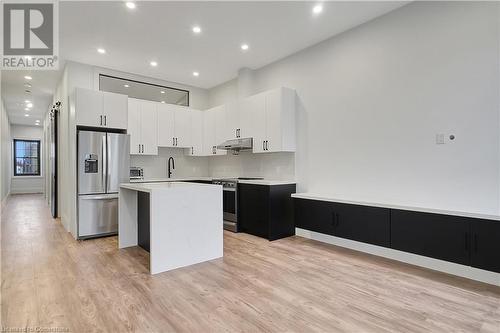 Kitchen with white cabinets, light wood-type flooring, a center island, and stainless steel appliances - 29 Main Street Unit# 201, Cambridge, ON - Indoor Photo Showing Kitchen With Upgraded Kitchen