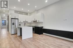 Kitchen with white cabinets, light wood-type flooring, a center island, and stainless steel appliances - 