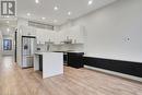 Kitchen with white cabinets, light wood-type flooring, a center island, and stainless steel appliances - 29 Main Street Unit# 201, Cambridge, ON  - Indoor Photo Showing Kitchen With Upgraded Kitchen 