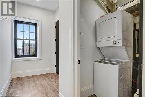 Laundry room featuring stacked washer and clothes dryer and light wood-type flooring - 29 Main Street Unit# 201, Cambridge, ON - Indoor Photo Showing Laundry Room