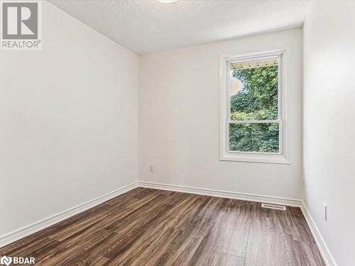 Empty room with a textured ceiling, a wealth of natural light, and dark wood-type flooring - 242 Lakeport Road Unit# 22, St. Catharines, ON - Indoor Photo Showing Other Room