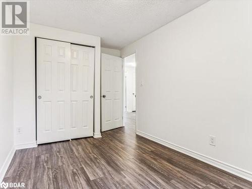 Unfurnished bedroom with dark hardwood / wood-style flooring, a textured ceiling, and a closet - 242 Lakeport Road Unit# 22, St. Catharines, ON - Indoor Photo Showing Other Room