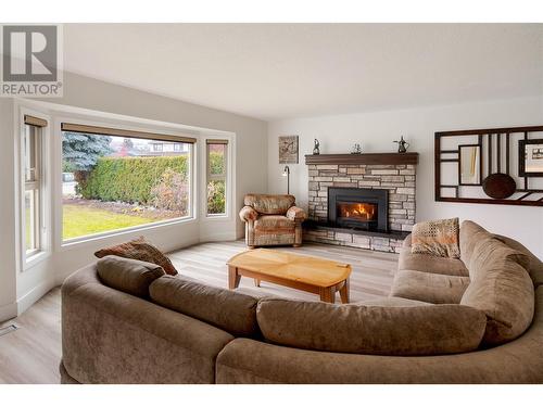 Living room with a gas fireplace and large windows - 600 Welke Road, Kelowna, BC - Indoor Photo Showing Living Room With Fireplace