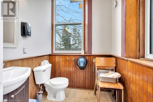 Bathroom featuring tile patterned flooring, sink, toilet, and wood walls - 5183 Trussler Road, Ayr, ON 