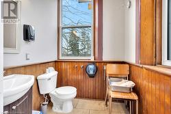 Bathroom featuring tile patterned flooring, sink, toilet, and wood walls - 