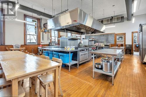 Kitchen featuring stainless steel fridge, wood walls, light hardwood / wood-style floors, a kitchen island, and exhaust hood - 5183 Trussler Road, Ayr, ON 