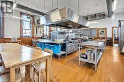 Kitchen featuring stainless steel fridge, wood walls, light hardwood / wood-style floors, a kitchen island, and exhaust hood - 