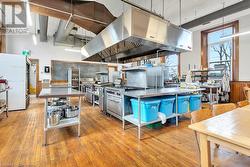 Kitchen featuring stainless steel range, range hood, white refrigerator, decorative light fixtures, and light wood-type flooring - 