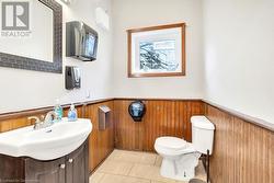 Bathroom with toilet, vanity, tile patterned floors, and wooden walls - 