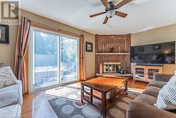 Living room with a brick fireplace, hardwood / wood-style floors, a textured ceiling, and ceiling fan - 