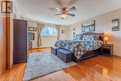 Bedroom with light hardwood / wood-style floors, a textured ceiling, and ceiling fan - 