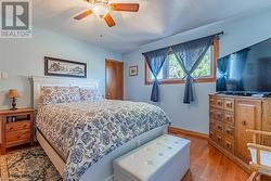 Bedroom with ceiling fan, a textured ceiling, and light wood-type flooring - 