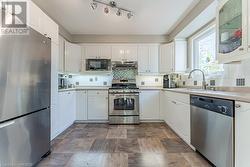 Kitchen featuring white cabinets, stainless steel appliances, and tasteful backsplash - 