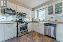 Kitchen with white cabinetry, decorative backsplash, stainless steel appliances, and sink - 