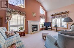 Living room featuring light carpet, a high ceiling, and a gas fireplace - 