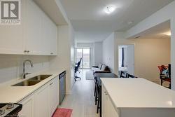 Kitchen featuring white cabinetry, dishwasher, sink, tasteful backsplash, and a kitchen breakfast bar - 