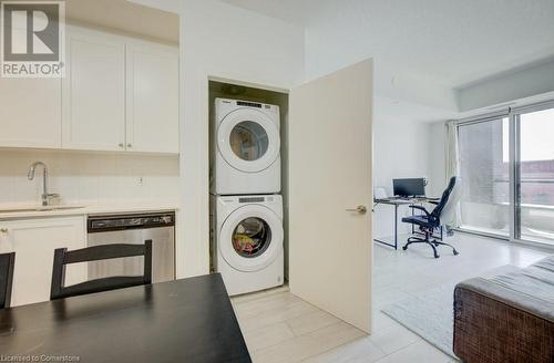 Laundry area with light tile patterned flooring, stacked washing maching and dryer, and sink - 55 Duke Street Unit# 322, Kitchener, ON - Indoor Photo Showing Laundry Room