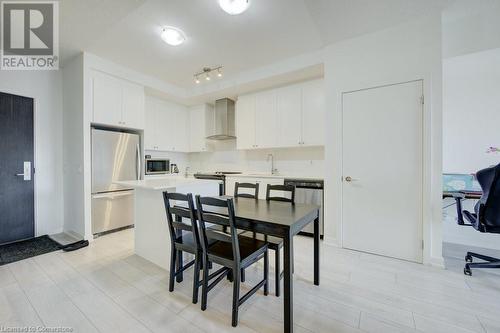 Kitchen featuring white cabinetry, sink, wall chimney range hood, and stainless steel appliances - 55 Duke Street Unit# 322, Kitchener, ON - Indoor