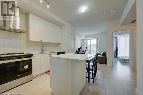 Kitchen featuring a center island, sink, wall chimney range hood, stainless steel range oven, and white cabinets - 55 Duke Street Unit# 322, Kitchener, ON - Indoor Photo Showing Kitchen