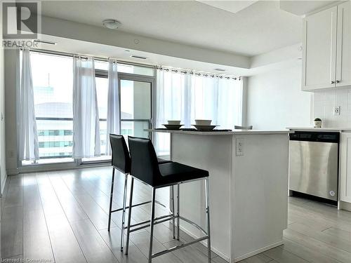 Kitchen with a breakfast bar, plenty of natural light, white cabinets, and stainless steel dishwasher - 55 Duke Street W Unit# 1210, Kitchener, ON - Indoor Photo Showing Kitchen