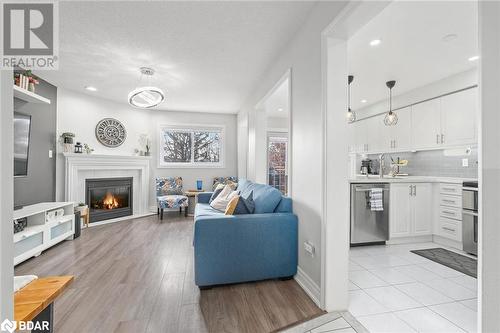 Living room with a fireplace, light wood-type flooring, a textured ceiling, and sink - 50 Smith Drive, Georgetown, ON - Indoor Photo Showing Living Room With Fireplace