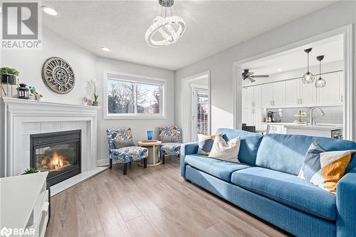 Living room featuring sink, light hardwood / wood-style flooring, a textured ceiling, a tiled fireplace, and ceiling fan with notable chandelier - 50 Smith Drive, Georgetown, ON - Indoor Photo Showing Living Room With Fireplace