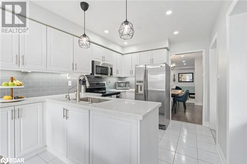 Kitchen with backsplash, white cabinetry, light tile patterned flooring, kitchen peninsula, and stainless steel appliances - 50 Smith Drive, Georgetown, ON - Indoor Photo Showing Kitchen With Upgraded Kitchen