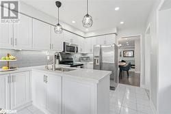 Kitchen with backsplash, white cabinetry, light tile patterned flooring, kitchen peninsula, and stainless steel appliances - 