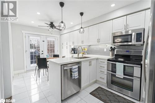 Kitchen featuring decorative backsplash, kitchen peninsula, stainless steel appliances, sink, and white cabinets - 50 Smith Drive, Georgetown, ON - Indoor Photo Showing Kitchen