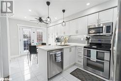 Kitchen featuring decorative backsplash, kitchen peninsula, stainless steel appliances, sink, and white cabinets - 