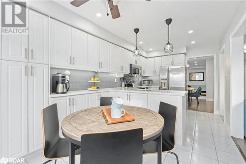 Kitchen with white cabinetry, stainless steel appliances, tasteful backsplash, pendant lighting, and light tile patterned floors - 50 Smith Drive, Georgetown, ON - Indoor