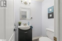 Bathroom with tile patterned flooring, vanity, an inviting chandelier, and toilet - 