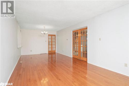 Spare room with french doors, light wood-type flooring, a textured ceiling, and an inviting chandelier - 15 Oakington Place, Mississauga, ON - Indoor Photo Showing Other Room