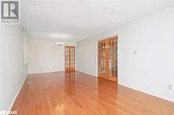 Spare room with french doors, light wood-type flooring, a textured ceiling, and an inviting chandelier - 