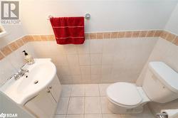 Bathroom featuring tile patterned flooring, vanity, toilet, and tile walls - 