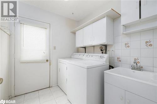 Washroom featuring cabinets, light tile patterned floors, tile walls, and washing machine and clothes dryer - 15 Oakington Place, Mississauga, ON - Indoor Photo Showing Laundry Room