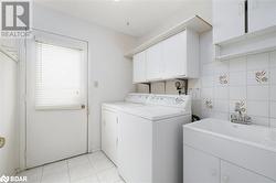 Washroom featuring cabinets, light tile patterned floors, tile walls, and washing machine and clothes dryer - 