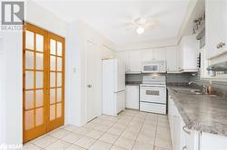 Kitchen with white cabinetry, french doors, sink, tasteful backsplash, and white appliances - 