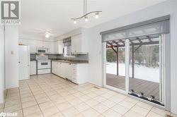 Kitchen featuring pendant lighting, white appliances, backsplash, white cabinets, and ceiling fan - 