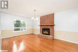 Unfurnished living room with hardwood / wood-style floors, a textured ceiling, a brick fireplace, and a notable chandelier - 