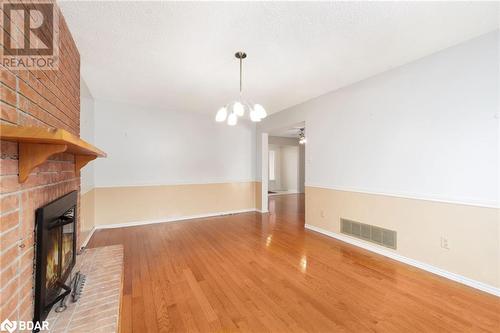 Unfurnished living room with a brick fireplace, ceiling fan with notable chandelier, a textured ceiling, and hardwood / wood-style flooring - 15 Oakington Place, Mississauga, ON - Indoor Photo Showing Other Room