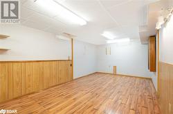 Basement with a drop ceiling, wood walls, and light wood-type flooring - 