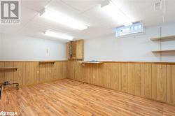 Empty room with a drop ceiling, wooden walls, and light hardwood / wood-style flooring - 