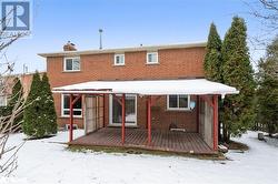 Snow covered rear of property featuring a wooden deck - 